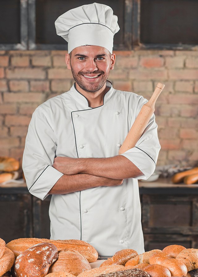 Panadero principal con traje de chef blanco cruzado de brazosy sosteniendo un palo de amasar